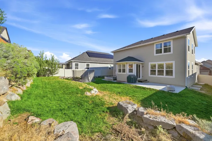 Expansive green lawn with tiered rock landscaping, concrete patio, and bay window