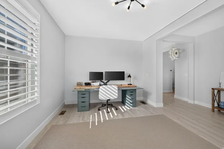 Light-toned wood-finish flooring, white plantation shutters, and a contemporary ceiling fixture