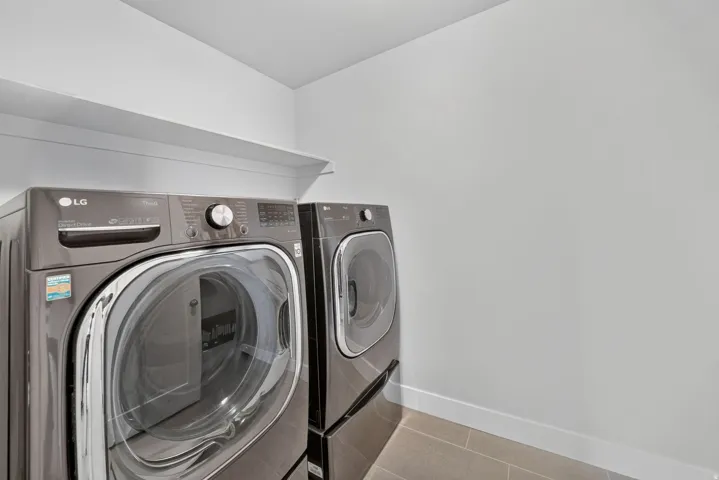 Laundry area with front-load washer and dryer set, built-in shelving, and tiled flooring