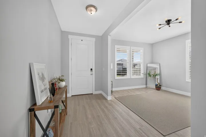 Light gray wall paint, wood-finish flooring, white plantation shutters, and a modern ceiling light fixture