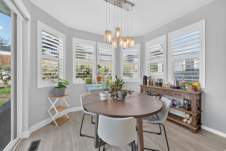 Dining area with wood-finish flooring, multiple windows featuring plantation shutters, and a sliding glass door