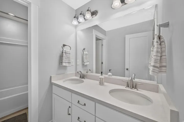 Dual undermount sinks with brushed nickel fixtures, a stone-finish countertop, and white shaker-style cabinetry