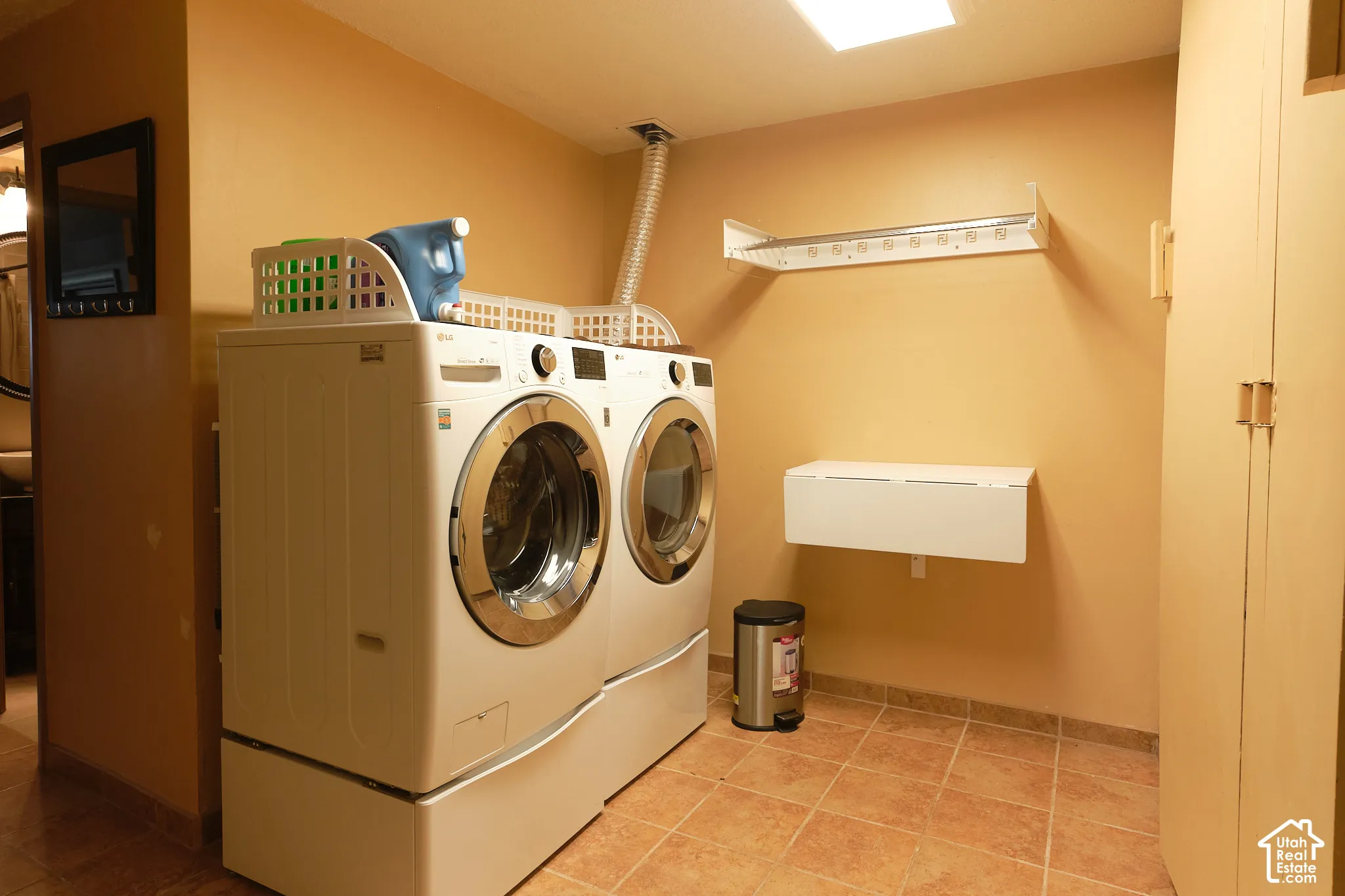Laundry area with tile flooring, built-in cabinetry, wall-mounted folding shelf, and overhead drying rack