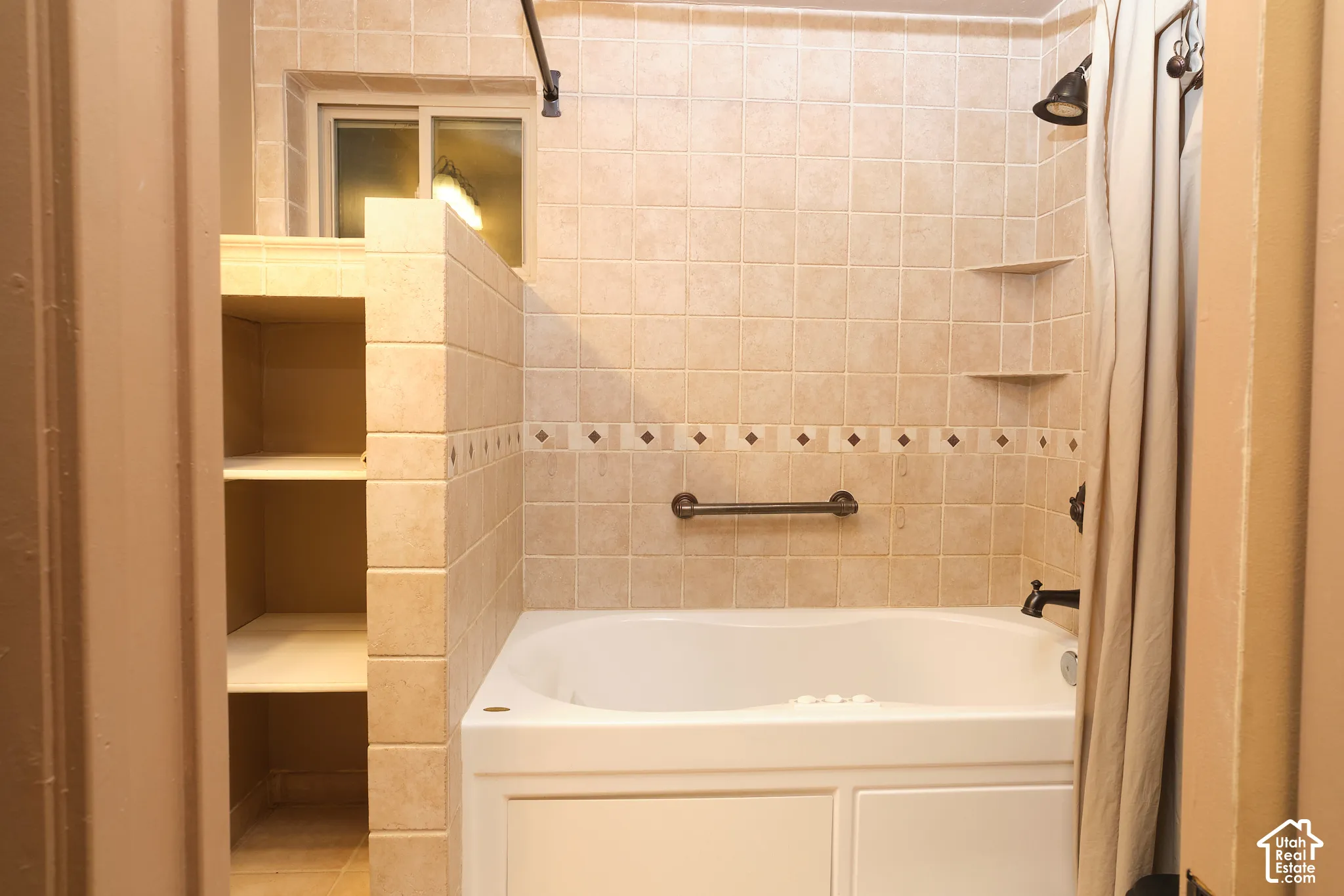 Jaccuzi bathtub with a tiled surround, built-in shelving.