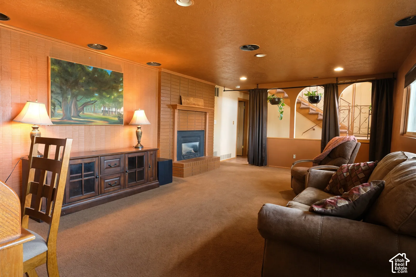 Brick fireplace with a raised hearth, recessed lighting, and decorative arched wall openings