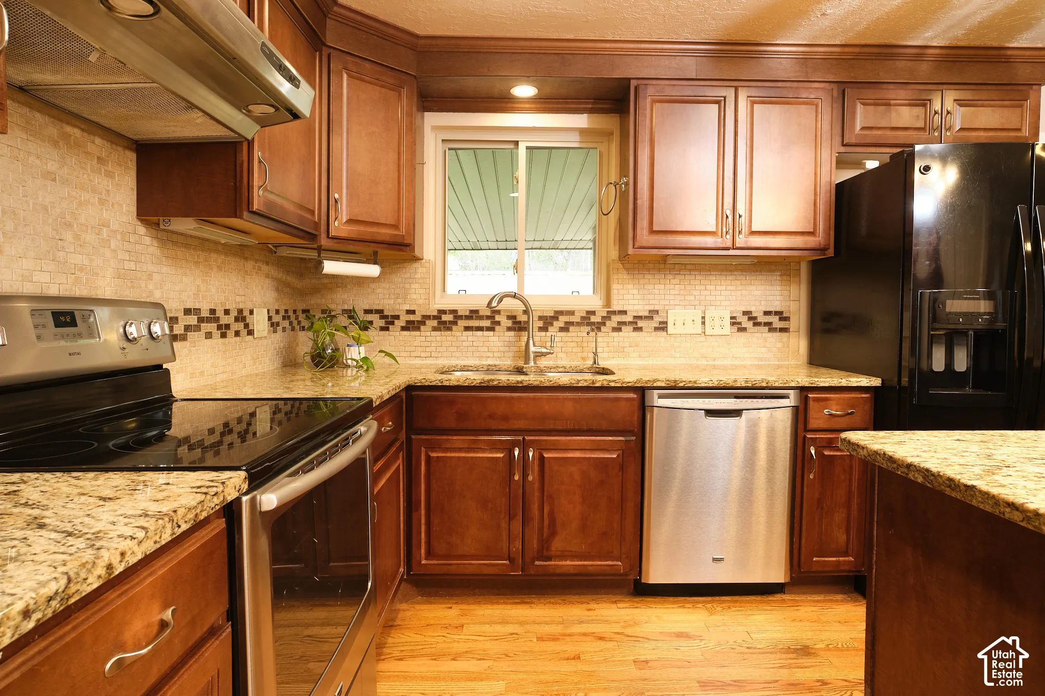 Hardwood flooring and granite countertops, stainless steel appliances, and a tiled backsplash