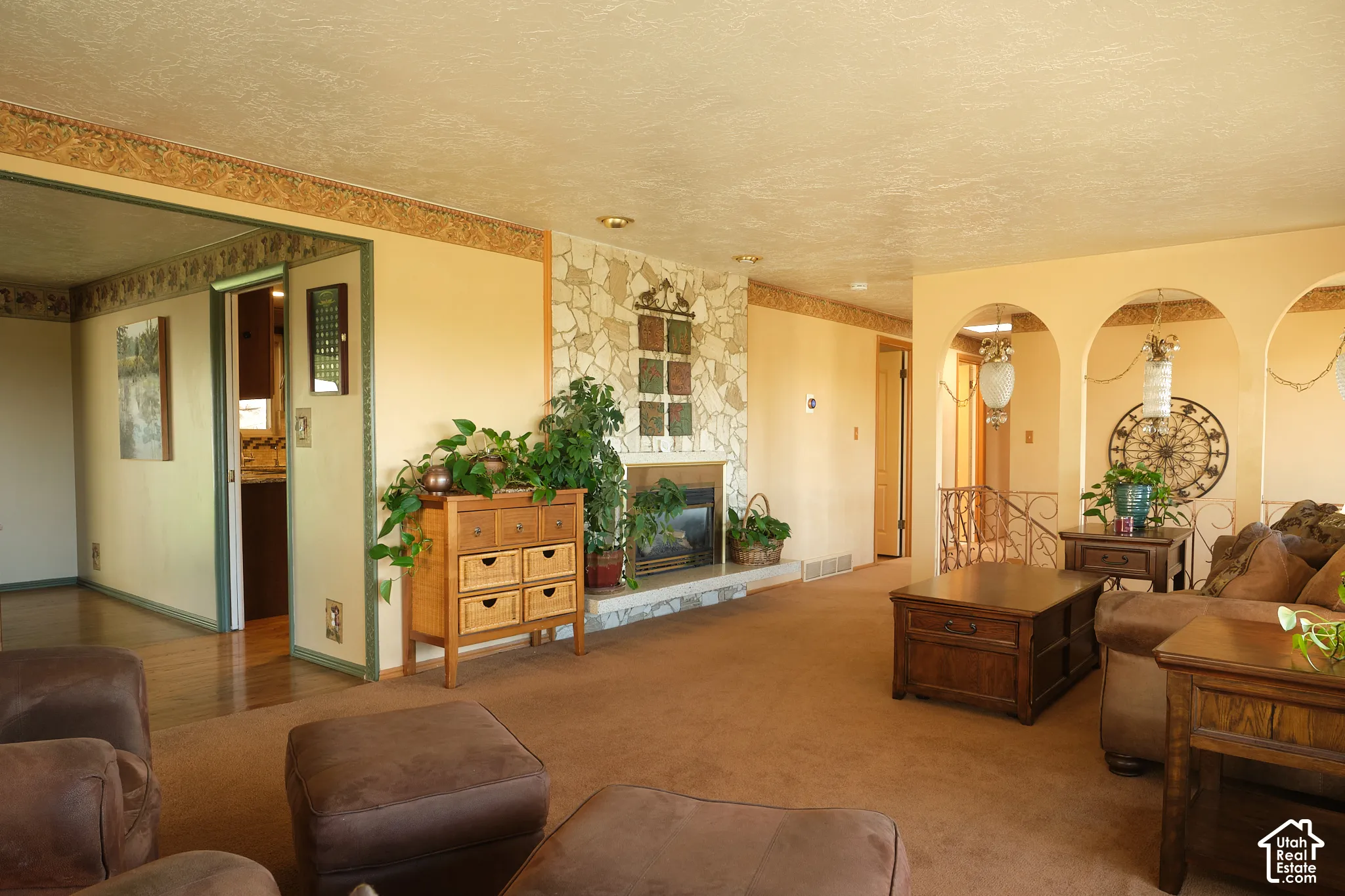Spacious living area featuring a stone-clad fireplace with hearth, arched wall openings.
