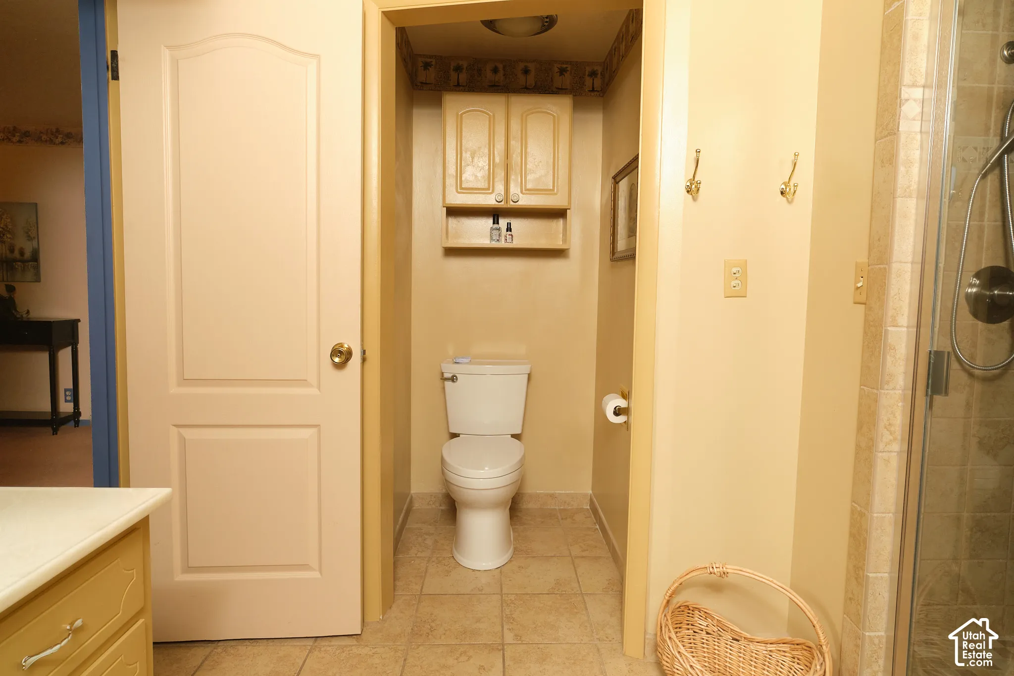 Recessed toilet area with built-in cabinetry and shelf, tile flooring, and a glass-enclosed shower