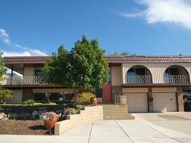 Split-level residence featuring a two-car garage, and an upper-level balcony.
