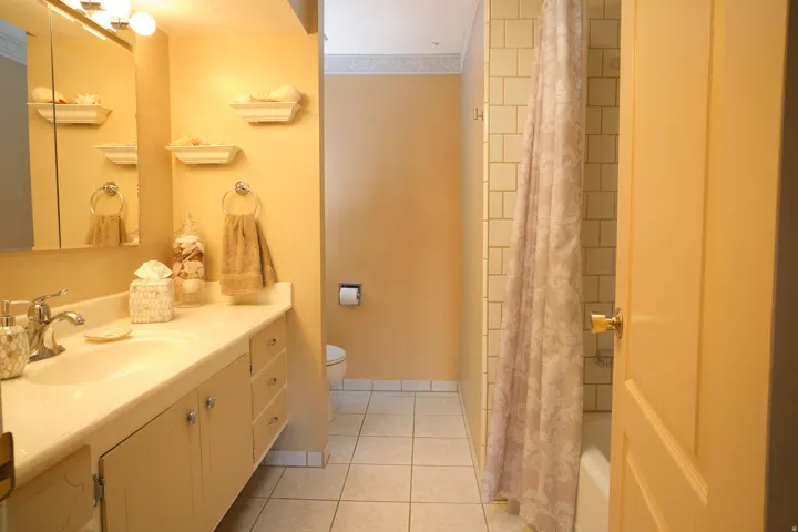 Bathroom featuring a single vanity with storage cabinetry, integrated sink, and wall-mounted mirror with overhead lighting