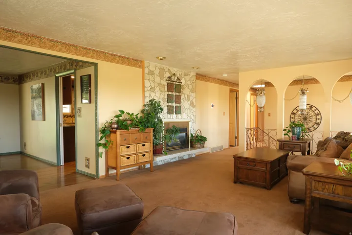Spacious living area featuring a stone-clad fireplace with hearth, arched wall openings, recessed lighting, and wood-finish flooring
