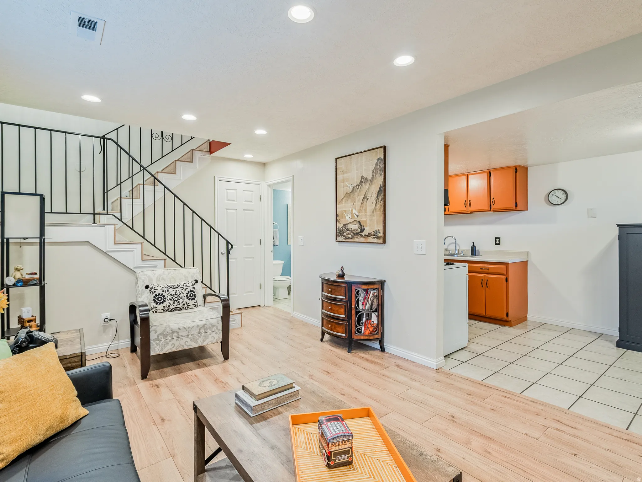 Wood-finish flooring, recessed lighting, and a black wrought iron railing