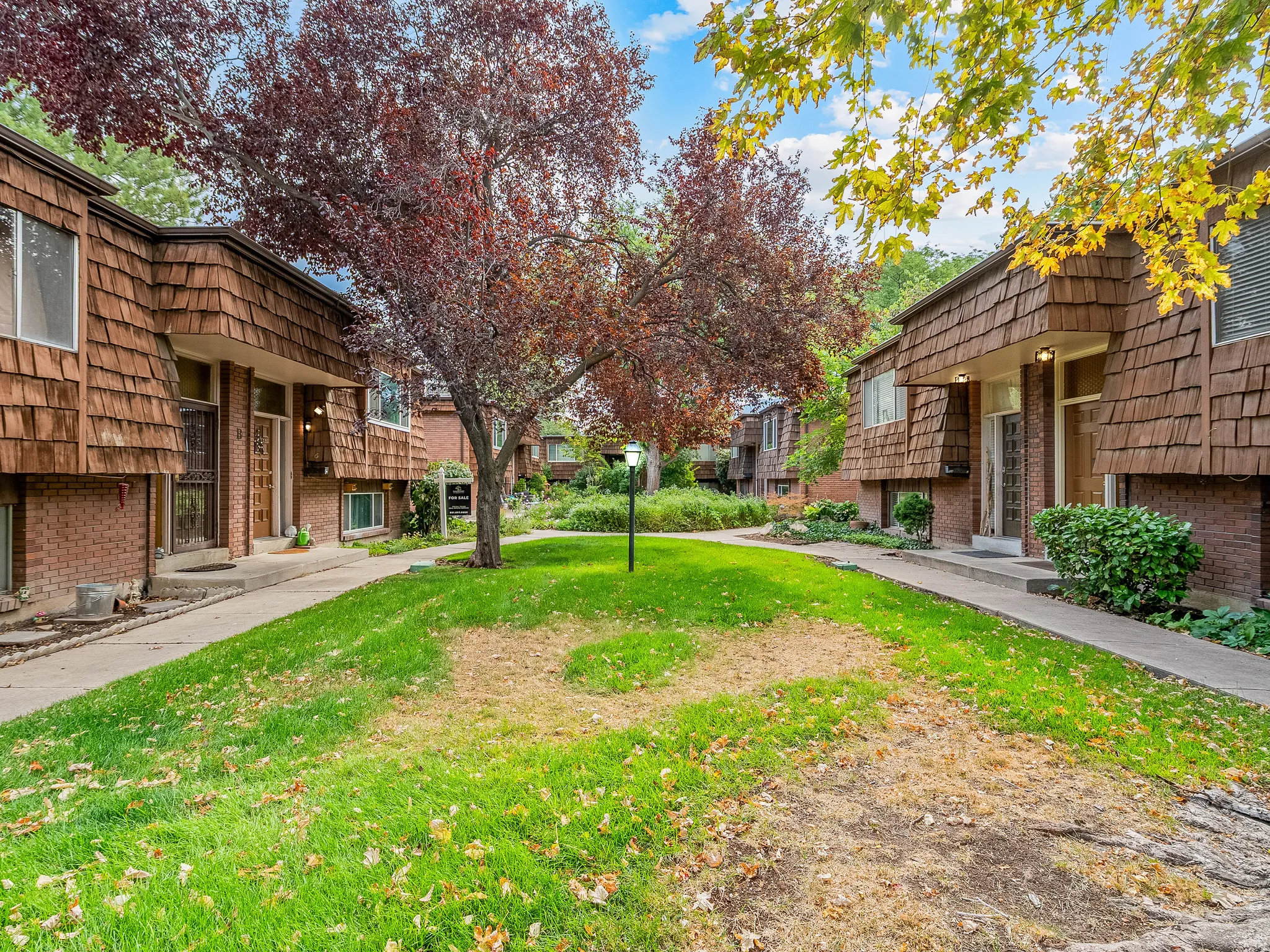 Townhome exterior featuring brick and wood shingle cladding