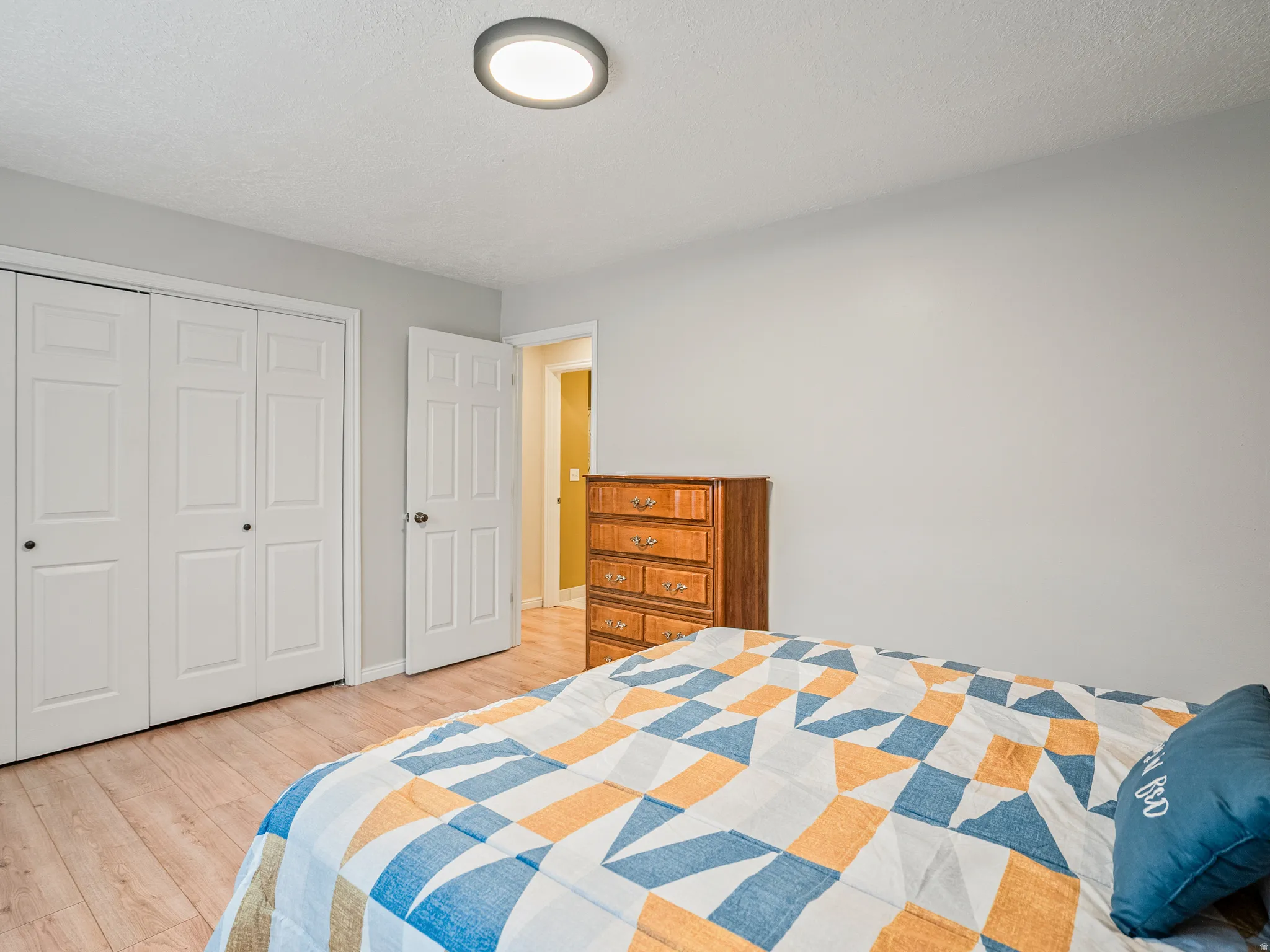 Recessed ceiling light fixture, light wood-finish flooring, white paneled bifold closet doors, and light gray wall paint
