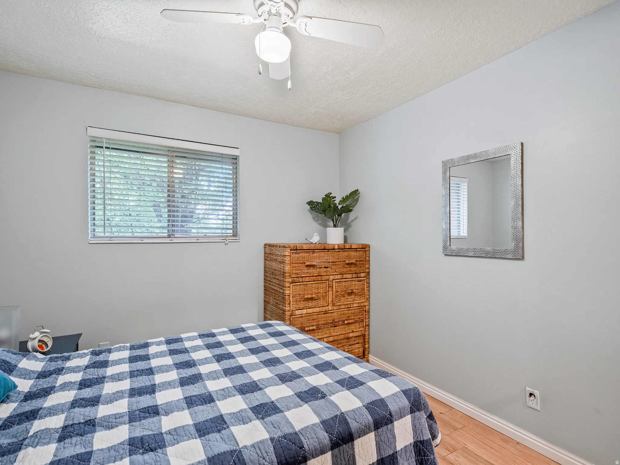 Window with horizontal blinds, ceiling fan with light fixture, wood-finish flooring, and light-toned walls