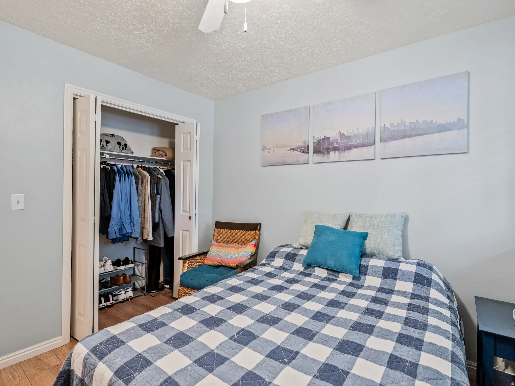 Built-in closet with bi-fold doors, overhead lighting, and wood-finish flooring