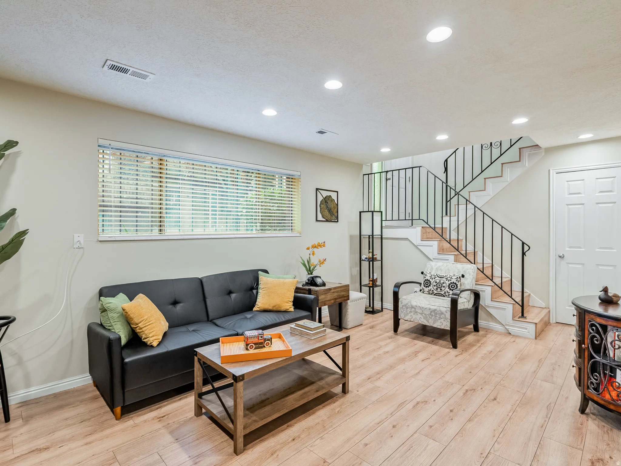 Recessed lighting, wood-finish flooring, staircase with metal railing, window with blinds, and paneled door