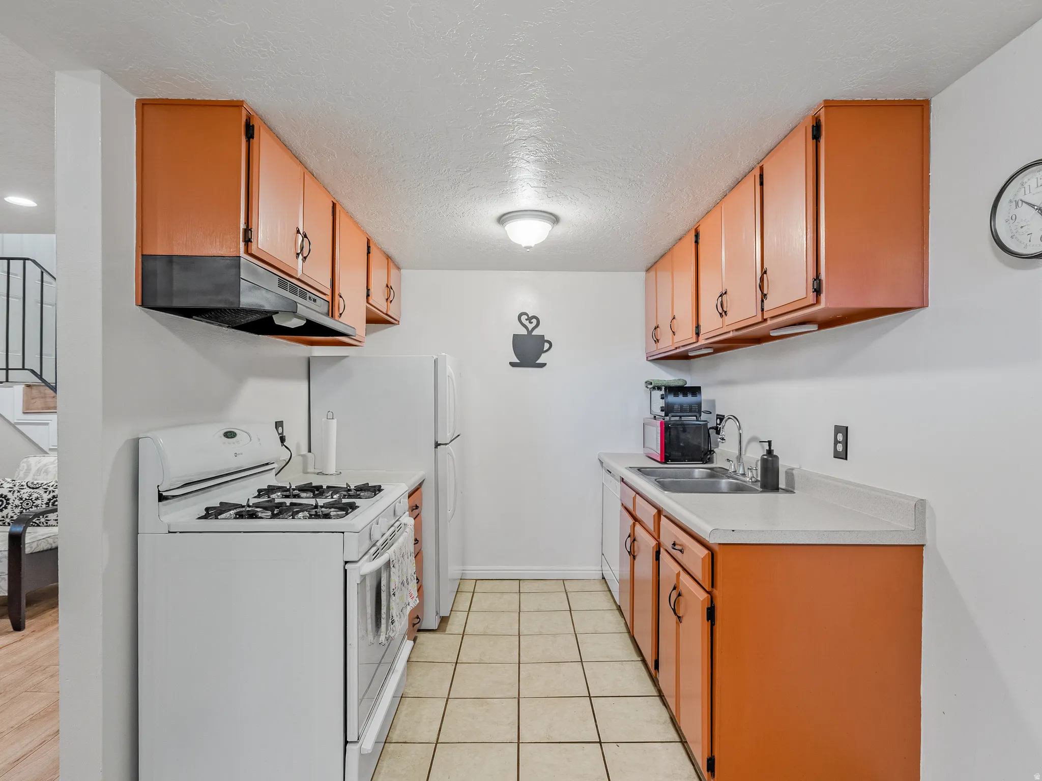 Galley kitchen featuring wood-finish cabinetry, white countertops, and tile flooring