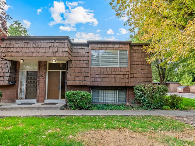 Cedar shake siding, brick facade, mature landscaping, front entry, lower-level window