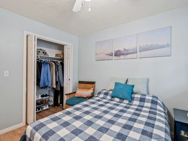 Built-in closet with bi-fold doors, overhead lighting, and wood-finish flooring