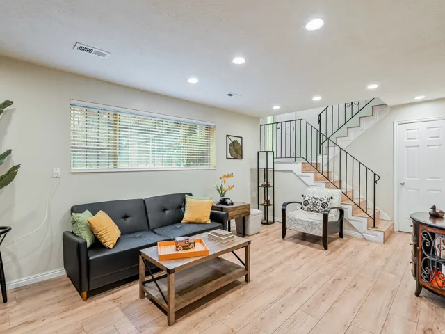 Recessed lighting, wood-finish flooring, staircase with metal railing, window with blinds, and paneled door