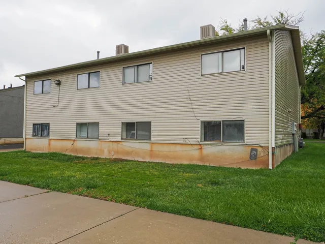 Two-story exterior with horizontal siding, multiple windows, and a concrete pathway