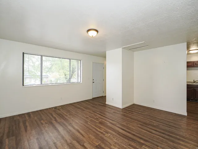 Wood-finish flooring, white walls, and a large window with white blinds