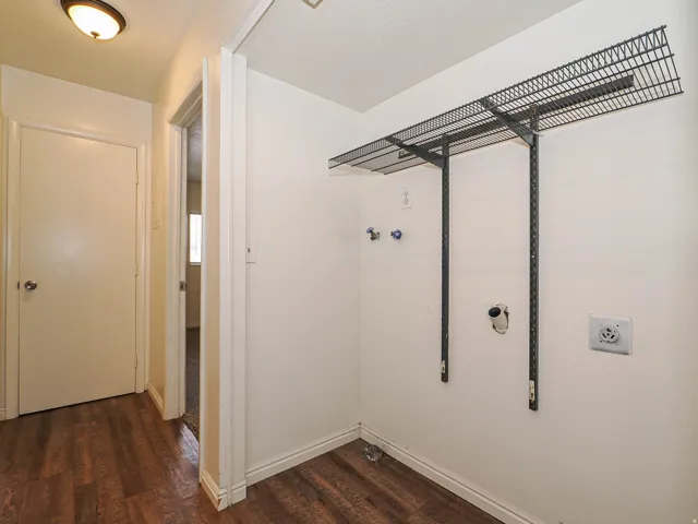 Dedicated laundry area featuring a wire storage shelf, utility hookups, and wood-finish flooring