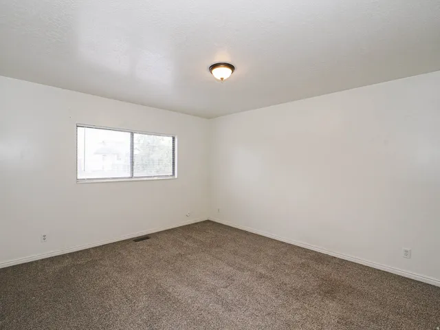 Neutral-toned carpeting, white painted walls, and a window for natural light