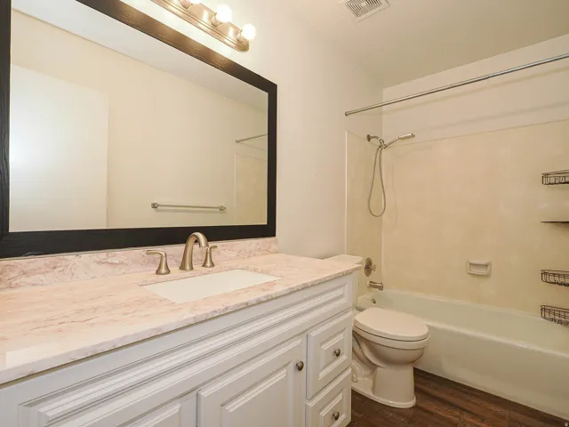 White vanity with paneled doors and drawers, light-colored countertop, rectangular undermount sink, and brushed nickel faucet. All nicely updated.