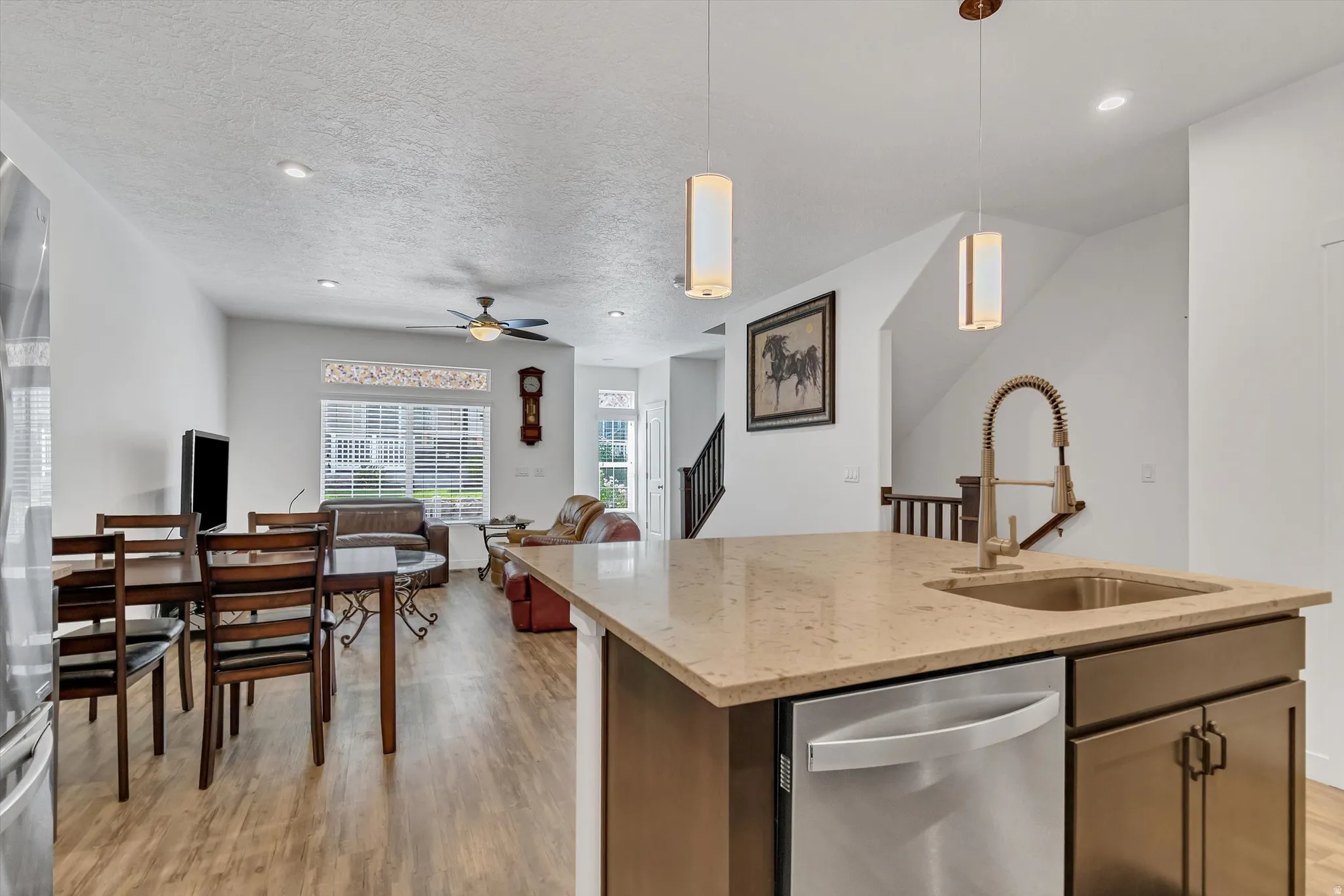 Kitchen island with stone countertop, integrated sink, and stainless steel dishwasher