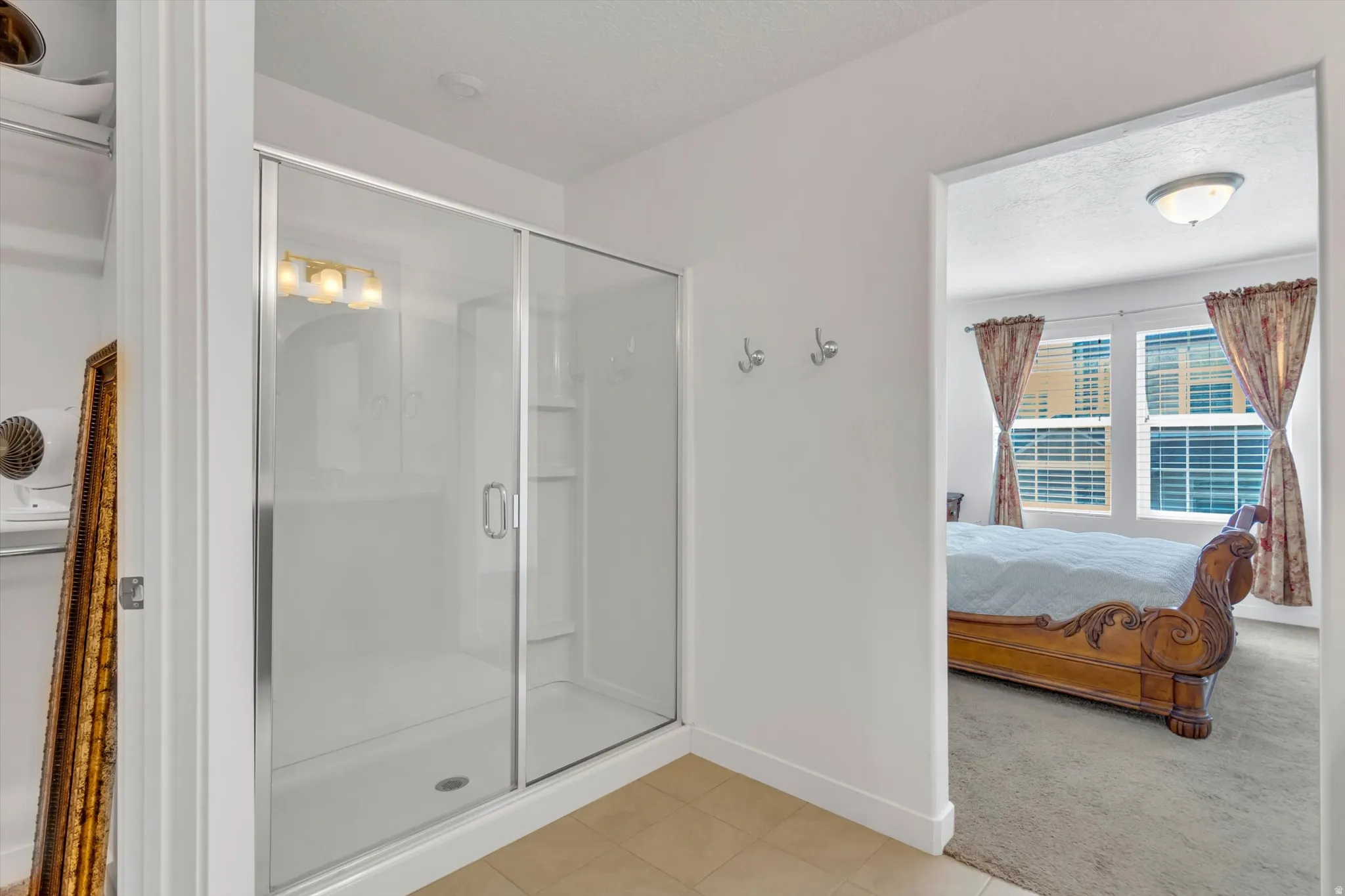Enclosed shower with sliding glass doors, integrated shelving, and a vanity light fixture