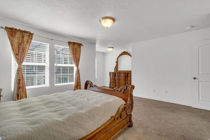 Carpeted flooring, white walls, two windows with blinds, and ceiling-mounted lighting