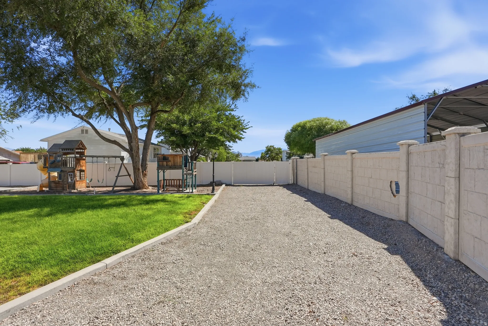 Expansive gravel driveway bordered by a concrete curb