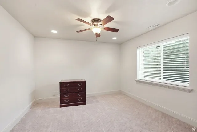 Recessed ceiling lighting, ceiling fan with integrated lighting, window with blinds, and light-toned carpeting