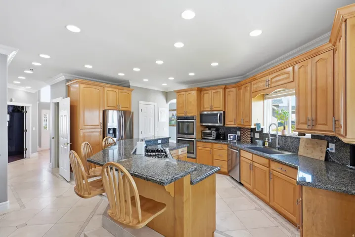 Kitchen featuring wood cabinetry, stainless steel appliances, granite countertops, and recessed lighting