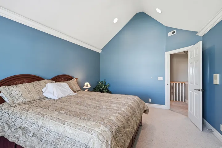 Vaulted ceiling with recessed lighting, crown molding, paneled interior door, and carpet flooring