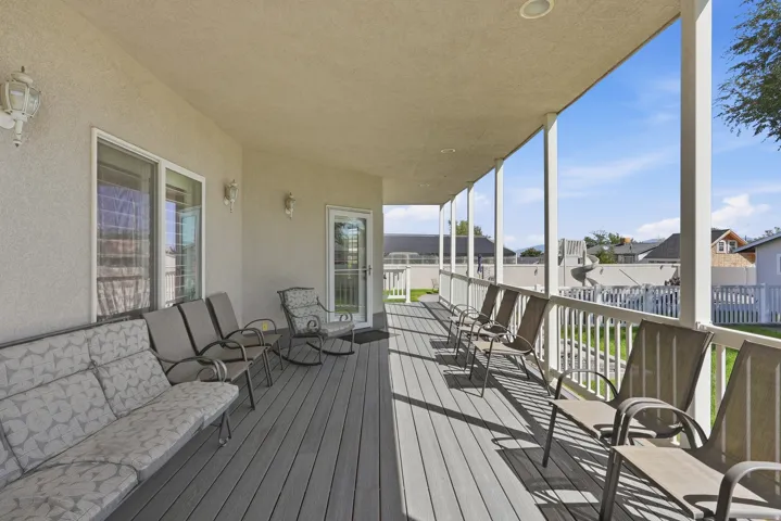 Expansive covered deck featuring a gray composite surface, white railing, and multiple support columns