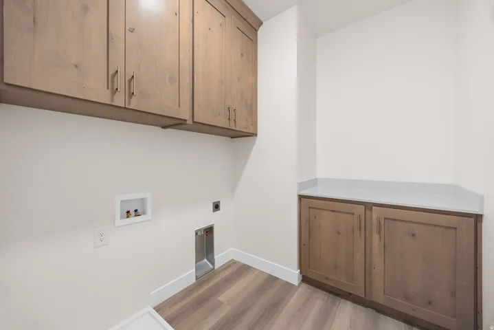 Wood-finish cabinetry, light-toned countertops, and wood-finish flooring