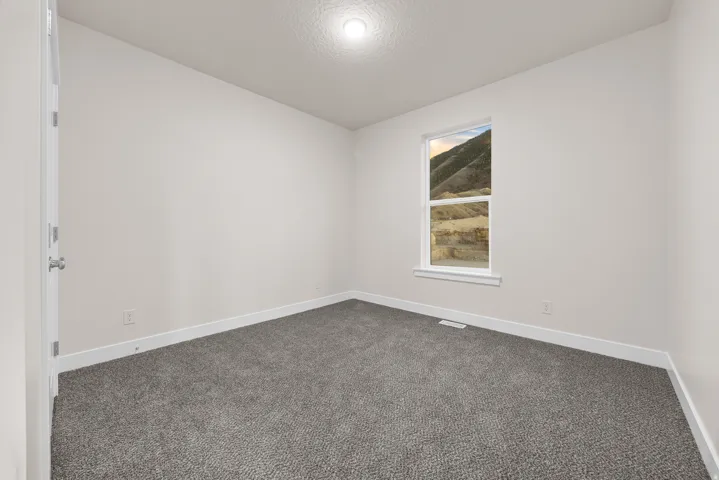 Neutral wall paint, textured carpet flooring, white trim, recessed lighting, and a single window with mountain scenery