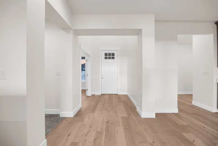 Entryway featuring wood-finish flooring, white trim, and a paneled front door with divided lites