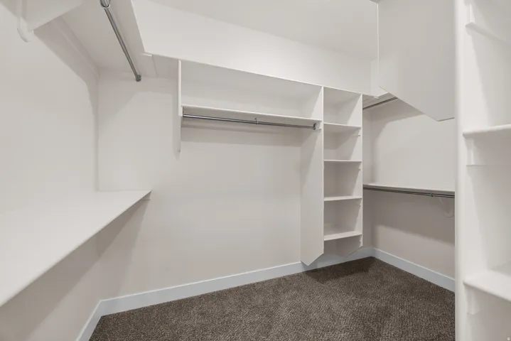 Custom closet system with white shelving, multiple hanging rods, and built-in vertical storage