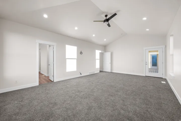 Vaulted ceiling with a ceiling fan, recessed lighting, carpet flooring, and a glass-paneled exterior door