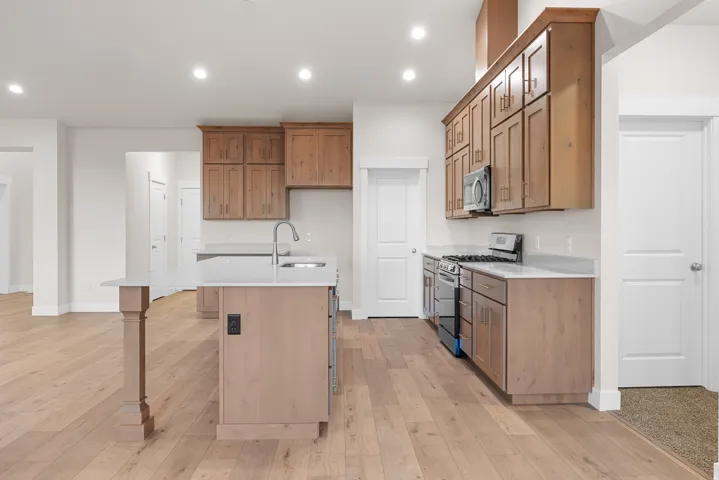 Kitchen featuring light wood-finish flooring, recessed lighting, wood-finish cabinetry, a central island with a sink, and stainless steel appliances