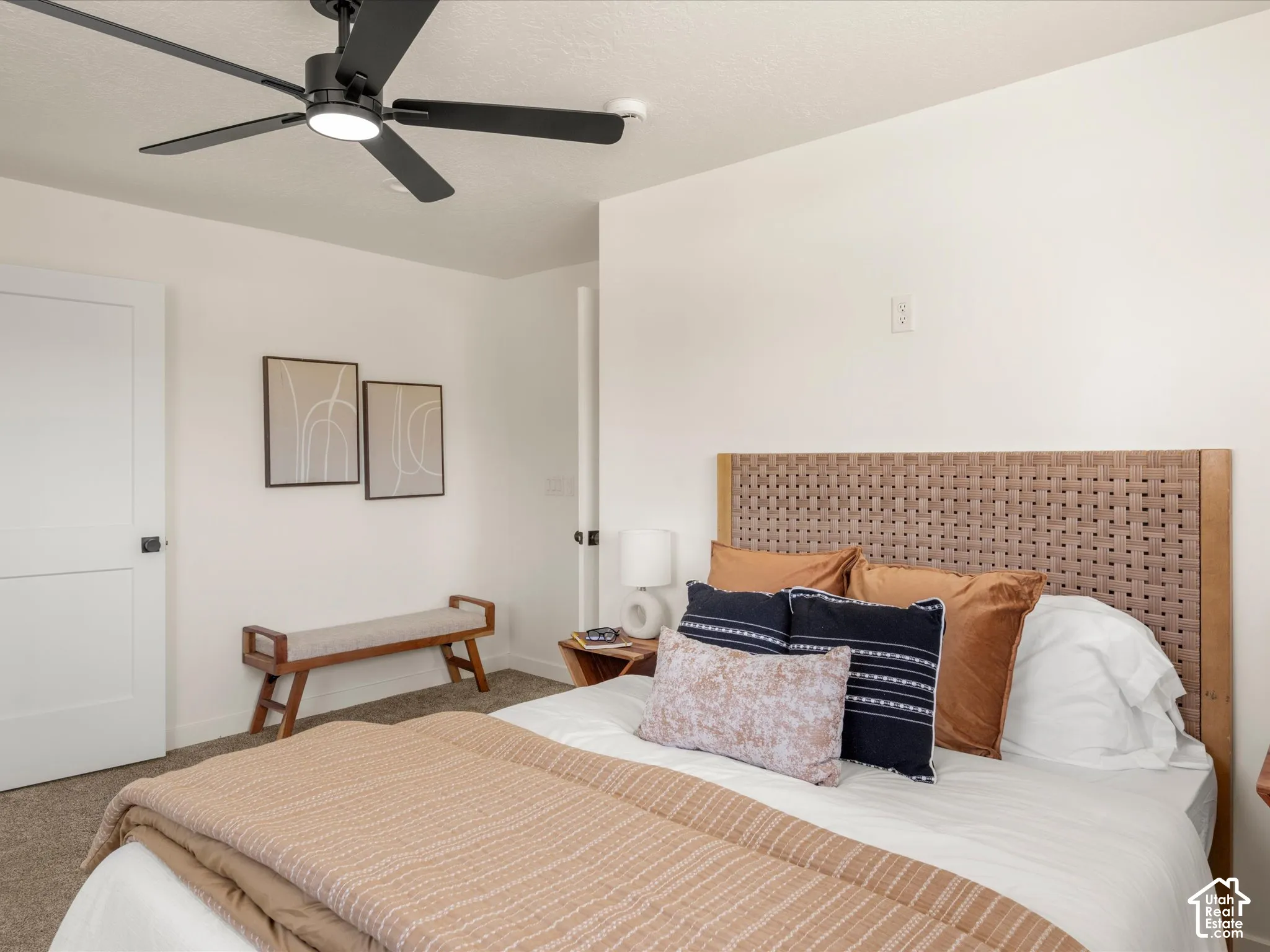 Primary Bedroom. White interior walls, black-finish ceiling fan, white paneled interior door, and a woven headboard