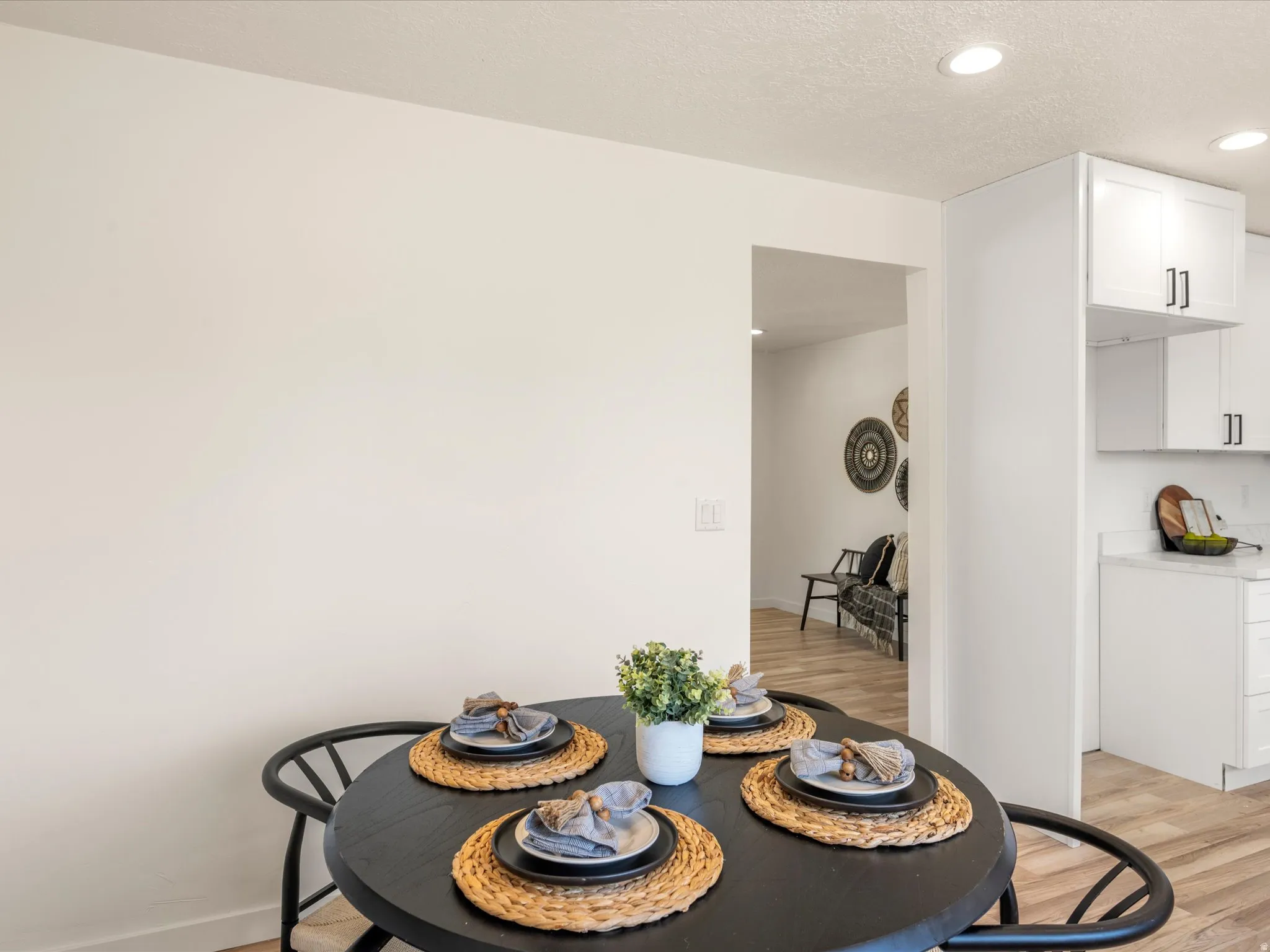 Recessed ceiling lighting, wood-finish flooring, white cabinetry, and light-toned countertops