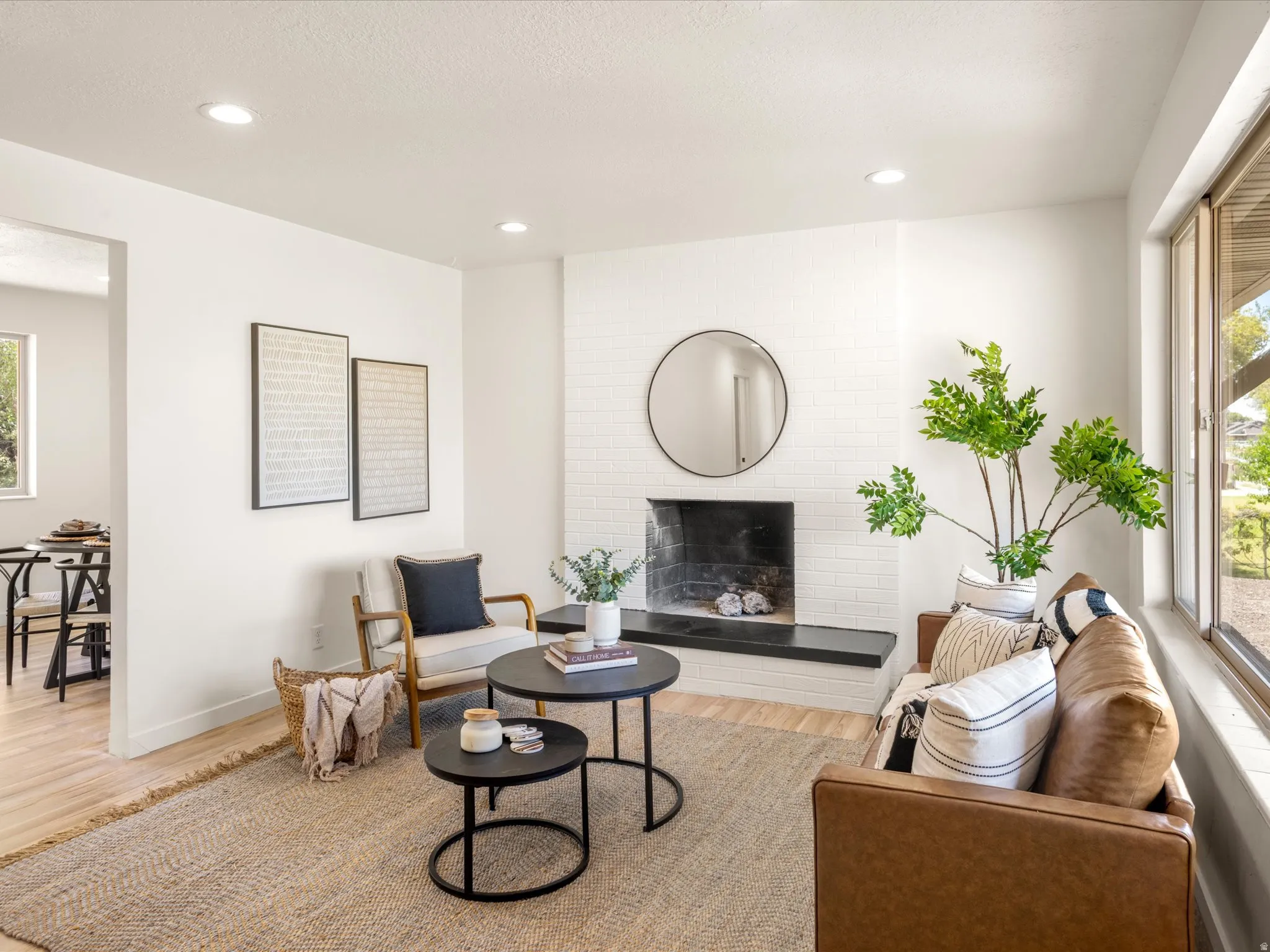 White painted brick fireplace with a dark stone hearth, recessed lighting, and large windows