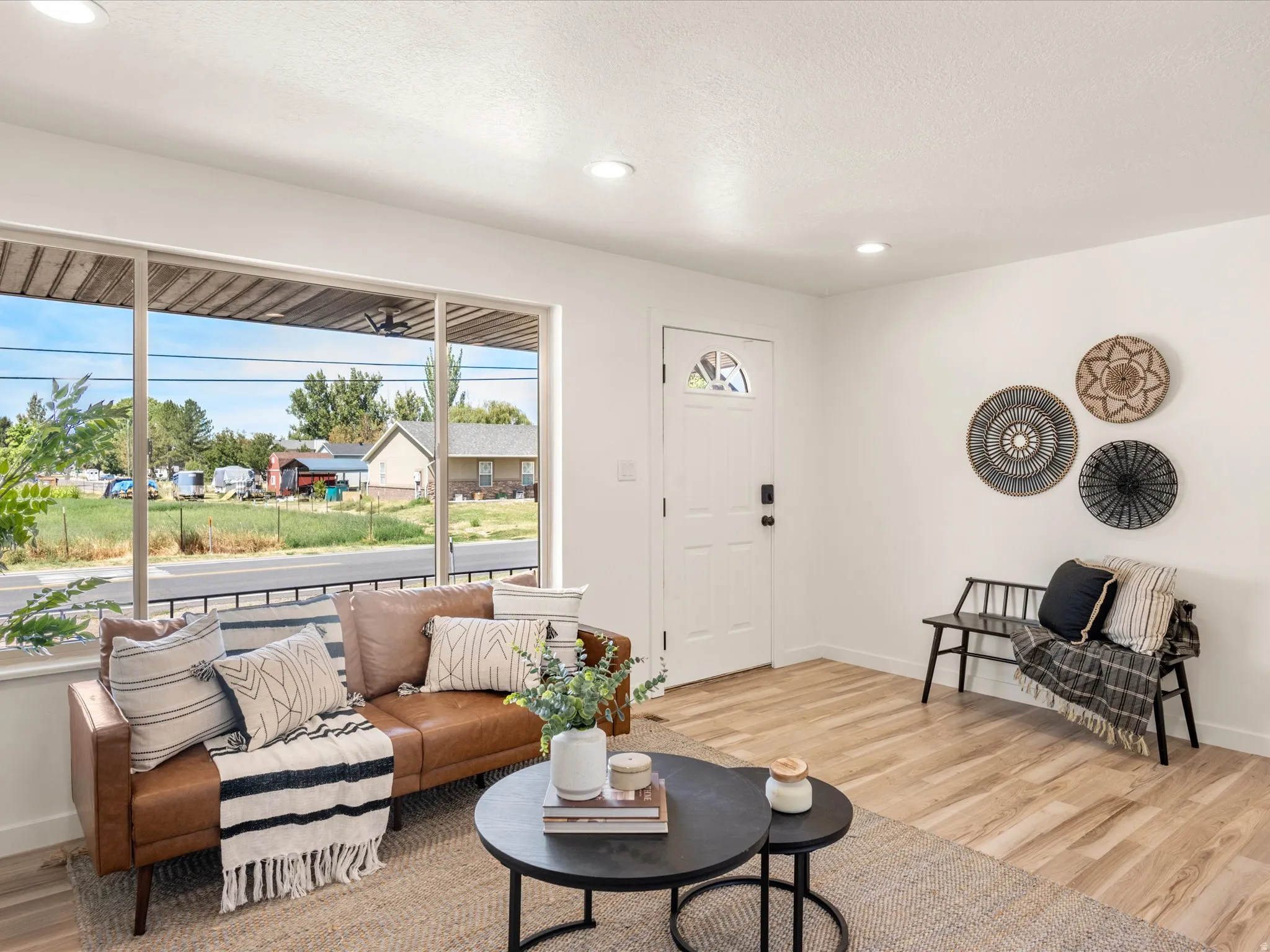 Expansive window, recessed lighting, wood-finish flooring, white entry door with glass insert, and a white wall finish