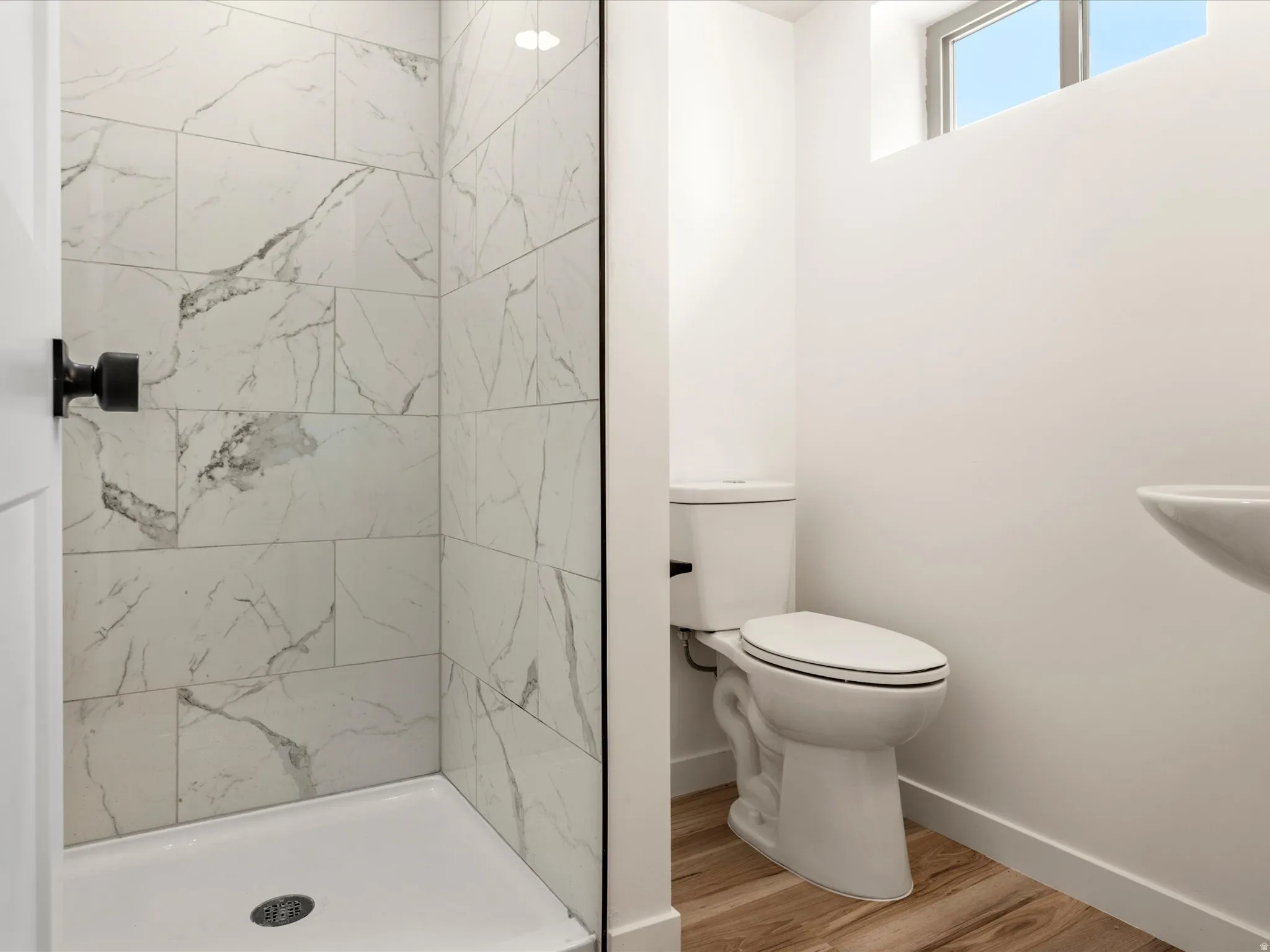 Basement Bathroom. Walk-in shower with white tile surround, glass enclosure, and matte black hardware