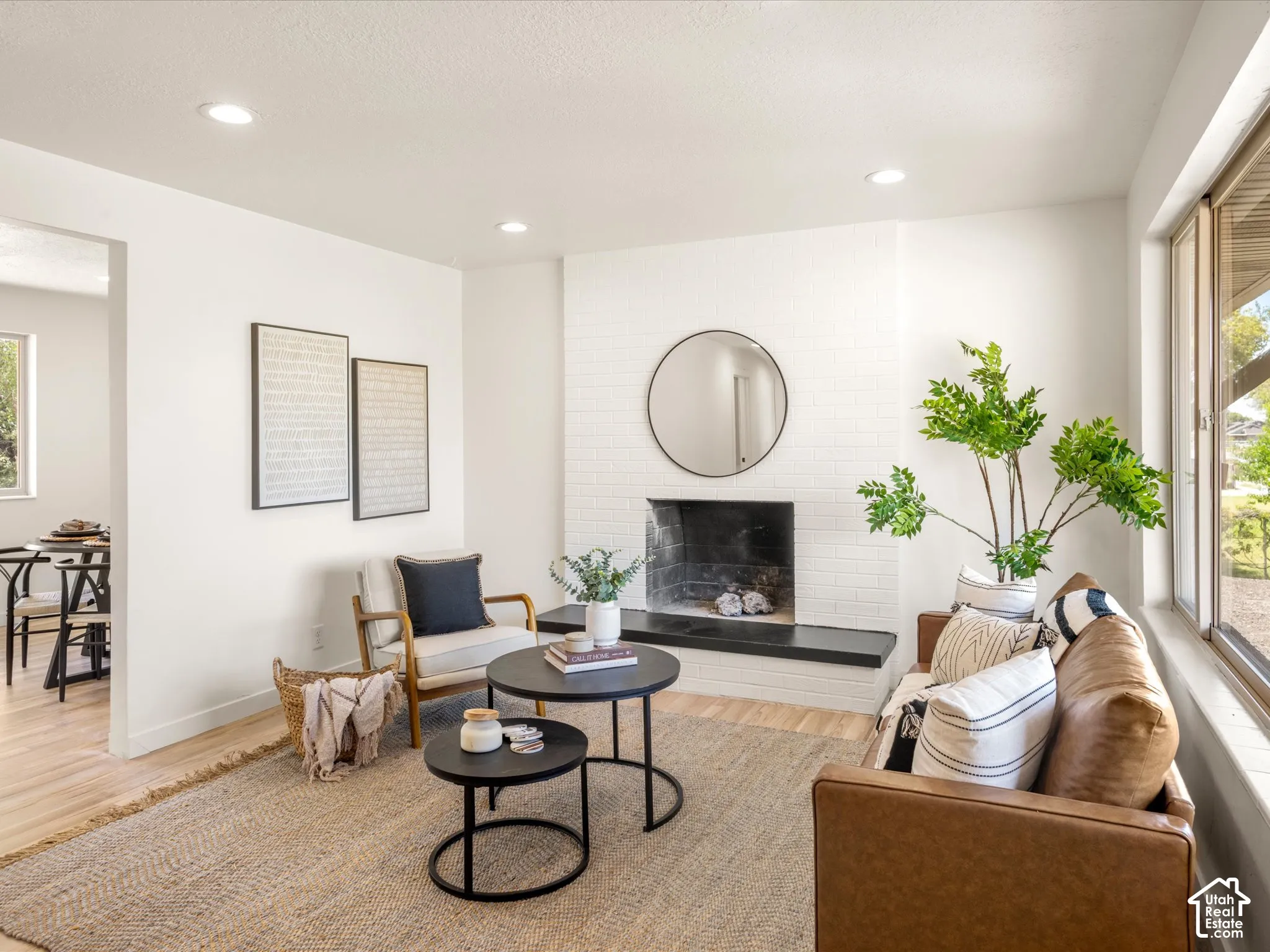 White painted brick fireplace with a dark stone hearth, recessed lighting, and large windows